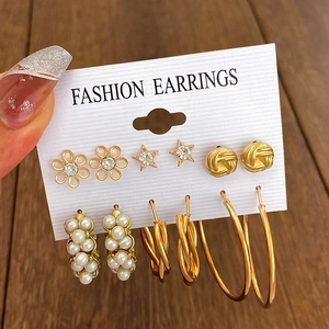 Detail van een 6-delige set gouden oorringen en parels gepresenteerd op een witte kaart