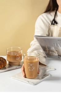 Close-up of cute cartoon bear glass cup held by hand with warm coffee inside
