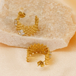 Detail of gold hollow mesh hoop earrings with sparkling zircon stones on stone display