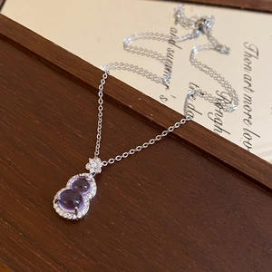 Detailed close-up of purple gourd necklace pendant with zircons on a wooden surface