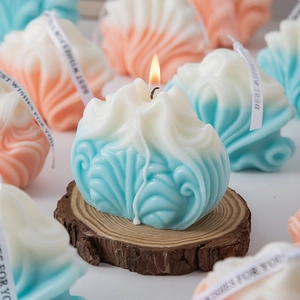 Close-up of shell-shaped candle with blue gradient and Best Wishes ribbon on wood base