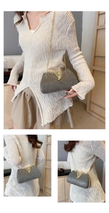 Detail of silver evening clutch bag with vertical texture, gold leaf clasp and chain strap