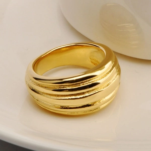 Close-up of a wide 18K gold plated titanium steel ring with textured horizontal grooves