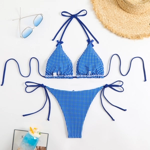 Flat lay of blue gingham halter bikini set with side-tie bottoms and summer beach accessories