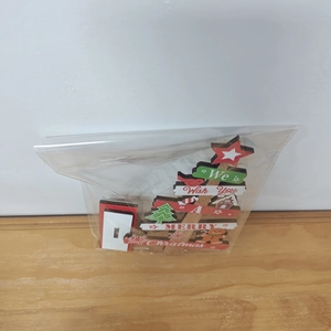 Christmas tree wooden ornament in plastic packaging on a wood table surface
