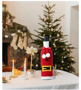 Close-up of a knitted Santa belt wine bottle cover on a festive holiday dinner table