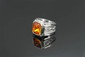 Detail of silver dragon ring with rectangular orange gemstone and intricate relief