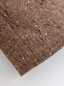 Gros plan sur le tissu en tweed à chevrons marron montrant la texture de la laine