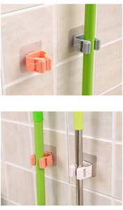 Wall-mounted mop holder details showing orange, grey, and white adhesive hooks for brooms