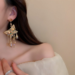 Dettaglio orecchini a farfalla dorati con nappine di cristallo su modella elegante