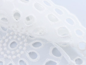 Detail der eleganten weißen Blumenstickerei mit zarten Ausschnittmustern auf dem Stoff