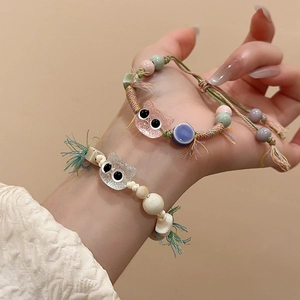 Detail of handmade ceramic cat bead bracelets with woven ropes and tassels on wrist
