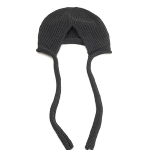 Dettaglio cappello in maglia grigio scuro con trama a coste e lunghi lacci paraorecchie