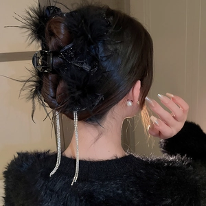 Detail of elegant black feather hair claw clip with sparkling rhinestone tassels for women