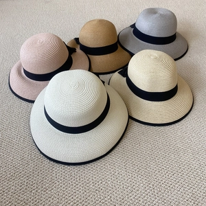 Vista plana de sombreros de paja en cinco colores con lazos decorativos de cinta negra