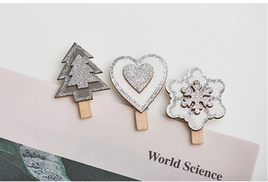 Close-up of wooden Christmas clips with silver glitter on heart and snowflake shapes