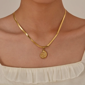 Elegant gold conch shell pendant on a snake chain necklace worn by a female model