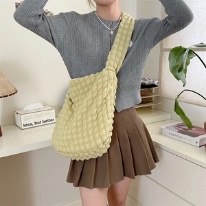 Detail of light yellow bubble texture tote bag with wide shoulder strap on model