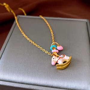 Detailed close-up of a white enamel carousel horse pendant on a gold chain necklace