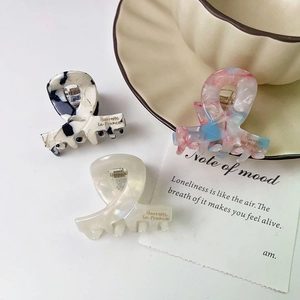 Three acetate hair claws in marble and pearl patterns with Barrette la France logo