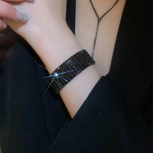 Gros plan d'un large bracelet manchette noir orné de strass scintillants sur le modèle