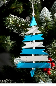 Blue and white wooden Christmas tree ornament hanging on pine branches with red berries