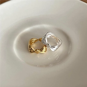 Detailed view of 925 sterling silver bow rings in gold and silver on ceramic plate