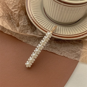 Detailed macro view of white pearls on golden metal hair clip against vintage background