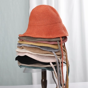 Vertical stack of colorful knitted bucket hats with chin straps on a wooden display stand
