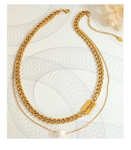 Detail of double-layer gold Cuban chain with rectangular nameplate and freshwater pearls