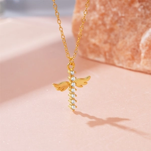 Macro view of gold cross angel wing pendant with shimmering cubic zirconia on pink rock