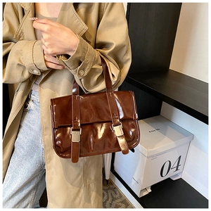 Detail of vintage brown satchel bag with silver buckles and glossy leather finish