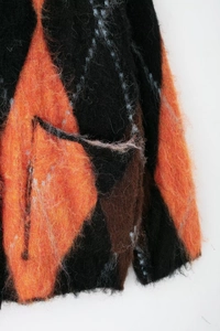 Détail du tricot à losanges duveteux avec une texture mohair orange et noire douce