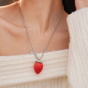 Dettaglio di un ciondolo a fragola in resina rossa con strass su una catena d'argento