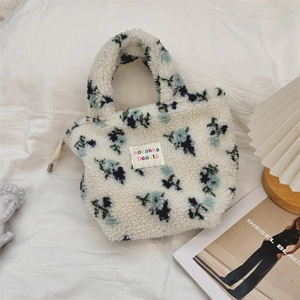 Nahaufnahme der flauschigen weißen Handtasche mit blauem Blumenmuster und Logo