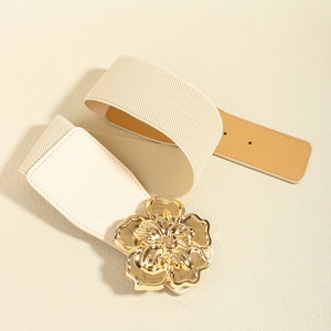 Détail de la ceinture élastique crème avec une grande boucle en métal doré en forme de fleur