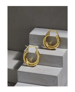 Detailed view of gold multi-layered twisted hoop earrings on industrial stone display