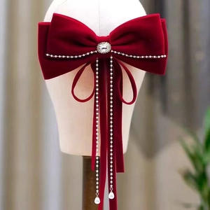 Detailed view of red velvet bow hair clip with pearl tassels and rhinestone center