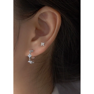 Close-up of S925 silver four-leaf clover earrings with white stone petals on a model