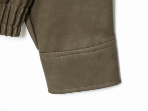 Détail de la manche en similicuir vert olive avec coutures aux poignets et plis élastiques