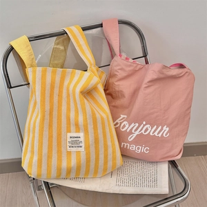 Borse tote in tela a righe gialle e rosa su una moderna sedia in metallo