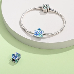 Detail of silver travel charm bracelet with blue and green palm tree enamel suitcase pendant