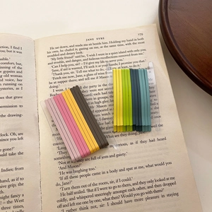 Colorful candy-colored bobby pins set arranged on cards against a vintage book background