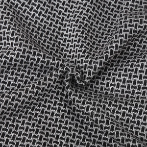 Close-up of the knitted fabric texture featuring a black and white geometric pattern