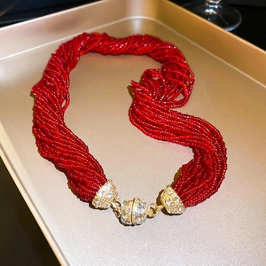 Close-up of multilayer red bead necklace featuring a sparkling crystal magnetic clasp
