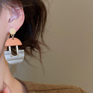 Close-up of a U-shaped resin drop earring with marble texture and amber stone details