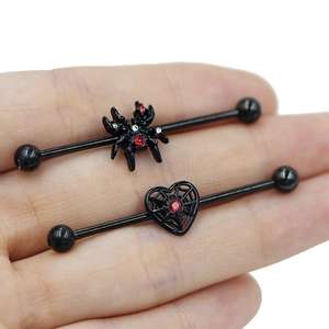 Detail view of black industrial barbells with red zircon spider and heart web designs