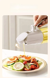 Detail view of gravity-sensing glass oil dispenser pouring over a fresh salad bowl