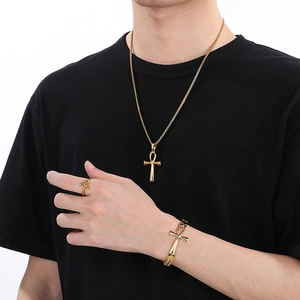 Detail view of a gold Ankh cross jewelry set including necklace, bracelet, and ring