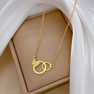 Detail of a matte gold butterfly pendant with interlocking rings in a gift box